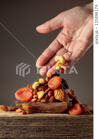 Mix of dried fruits is poured in a wooden dish. Mix of dried fruits is poured in a wooden dish. 135896174