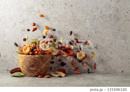 Mix of dried fruits and nuts on a gray stone table. 135896180