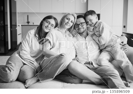 Lovely portrait of family chilling together at home. Big family lying on couch and hugging. Cute moments of time with siblings in modern living room. Black and white image. Lovely portrait of family chilling together at home. Big family lying on couch and hugging. Cute moments of time with siblings in modern living room. Black and white image. 135896509