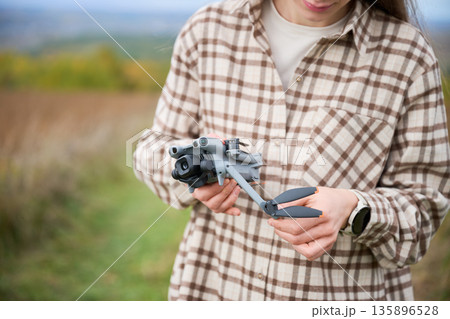 A person is getting ready to fly a drone while standing in a vibrant meadow under a clear blue sky. The landscape is peaceful and inviting. A person is getting ready to fly a drone while standing in a vibrant meadow under a clear blue sky. The landscape is peaceful and inviting. 135896528