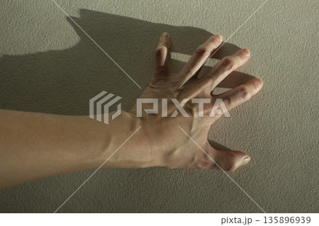 A woman's hand with bulging tendons	 135896939