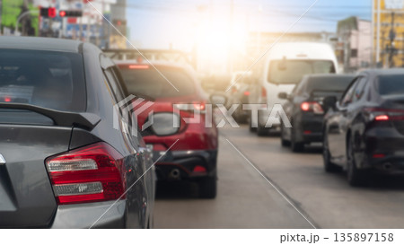 Rear side of cars on the concrete road stop by traffic red light control. Many cars on the road heading towards the goal of the trip. Town with light under sky for background. Rear side of cars on the concrete road stop by traffic red light control. Many cars on the road heading towards the goal of the trip. Town with light under sky for background. 135897158