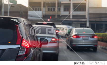 Driving of cars on the asphalt road with turn on brake ligt. Ready to park and queue on the street. Stop by traffic red light control in the city at morning time. 135897160