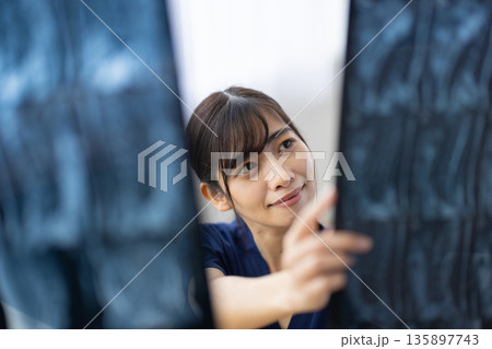 レントゲン画像を見る紺色の医療用スクラブを着た若い日本人女性 レントゲン画像を見る紺色の医療用スクラブを着た若い日本人女性 135897743