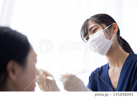歯科用の器具を持って患者の歯をチェックする若い歯科医師の女性 歯科用の器具を持って患者の歯をチェックする若い歯科医師の女性 135898091