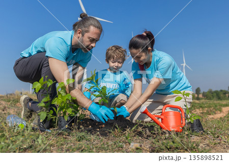 Family helping planting tree in garden for save world on wind turbine field background Family helping planting tree in garden for save world on wind turbine field background 135898521