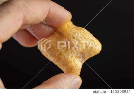crispy mashed potato chips fried in a large amount of sunflower oil, sprinkled with red hot pepper spices, crispy high-calorie chips with spices are scattered on the table crispy mashed potato chips fried in a large amount of sunflower oil, sprinkled with red hot pepper spices, crispy high-calorie chips with spices are scattered on the table 135898934