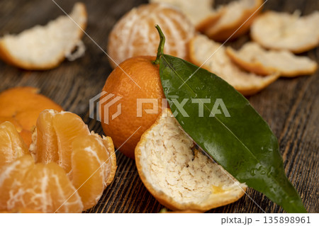 ripe orange and juicy and peeled tangerines are lying on a wooden table, ripe tangerines are small in size and the peel of peeled tangerines on a wooden table ripe orange and juicy and peeled tangerines are lying on a wooden table, ripe tangerines are small in size and the peel of peeled tangerines on a wooden table 135898961