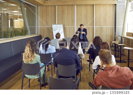 Mature business man speaker talking about work project for a company employees in meeting room. Mature business man speaker talking about work project for a company employees in meeting room. 135899185