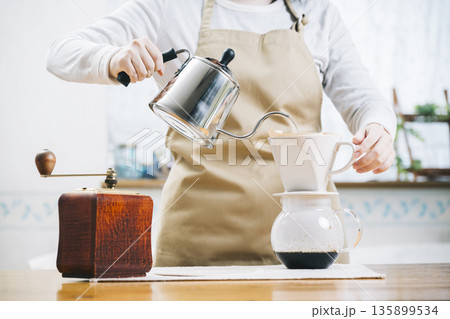 コーヒーカップにコーヒーを注ぐ女性 135899534
