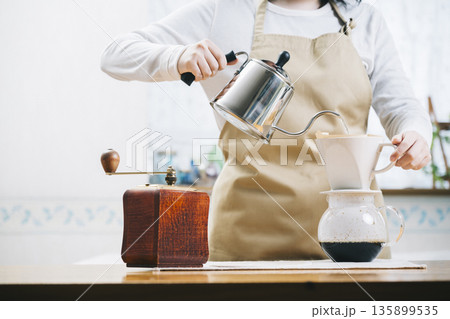 コーヒーカップにコーヒーを注ぐ女性 135899535