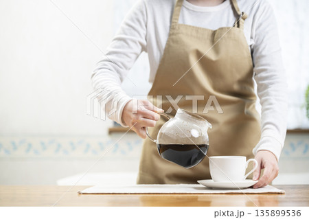 コーヒーカップにコーヒーを注ぐ女性 135899536