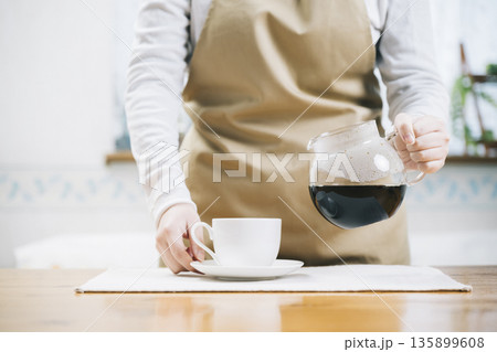 コーヒーカップにコーヒーを注ぐ女性 135899608