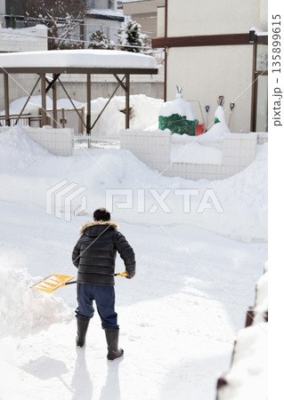 除雪スコップで雪かきをしているシニア男性の後ろ姿 除雪スコップで雪かきをしているシニア男性の後ろ姿 135899615