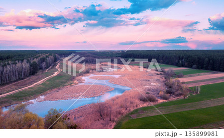Panoramic view from above of the countryside, winding river, and sky during sunset. Rural landscape in spring 135899981