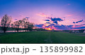 Rural landscape with beautiful evening sky at sunset. Green field and village on the horizon 135899982