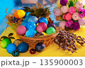 Colorful easter eggs in a basket on a yellow wooden table 135900003