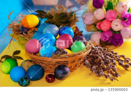 Colorful easter eggs in a basket on a yellow wooden table Colorful easter eggs in a basket on a yellow wooden table 135900003