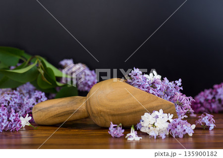 Lilac in a wooden scoop on a black background Lilac in a wooden scoop on a black background 135900182