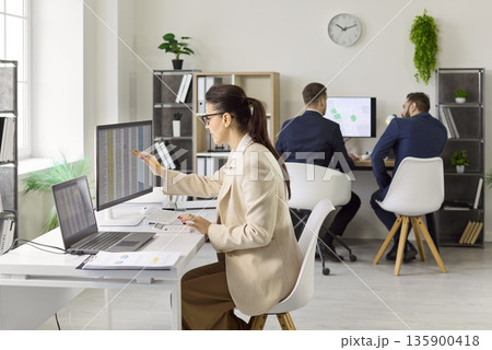 Focused auditor reviewing financial data on dual monitors in contemporary office Focused auditor reviewing financial data on dual monitors in contemporary office 135900418