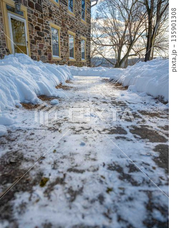 Low angle view of cleared walkway to houise front door after snow storm winter scene Low angle view of cleared walkway to houise front door after snow storm winter scene 135901308