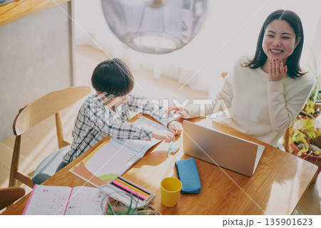 勉強する子供とリモートワーク中の親 135901623
