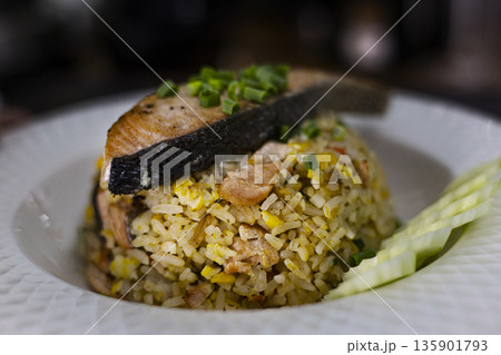 Salmon Fried Rice With Grilled Salmon On Ceramic Plate, A mouthwatering photo of salmon fried rice, flaky salmon on rice with green onions, for healthy gourmet or seafood delight documentary. Salmon Fried Rice With Grilled Salmon On Ceramic Plate, A mouthwatering photo of salmon fried rice, flaky salmon on rice with green onions, for healthy gourmet or seafood delight documentary. 135901793
