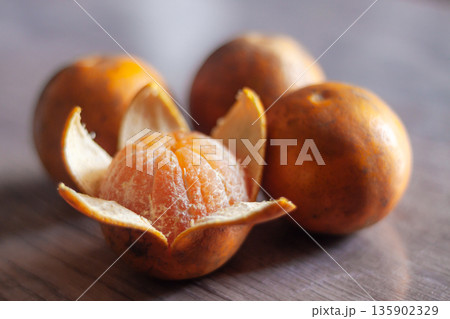 Fresh peeled mandarin with whole fruits on wooden table in soft natural light, close-up still life. Fresh peeled mandarin with whole fruits on wooden table in soft natural light, close-up still life. 135902329