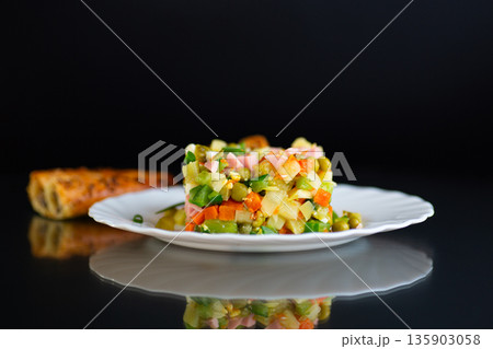 Classic Olivier salad with mixed vegetables on a black background Classic Olivier salad with mixed vegetables on a black background 135903058