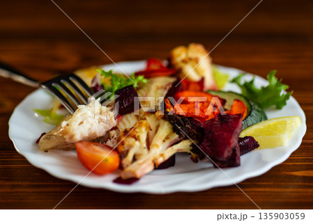 Fresh baked fish served with vegetables and lemon 135903059