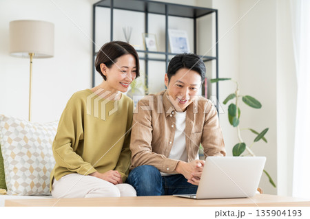 リビングでパソコンを見るミドルの夫婦 リビングでパソコンを見るミドルの夫婦 135904193