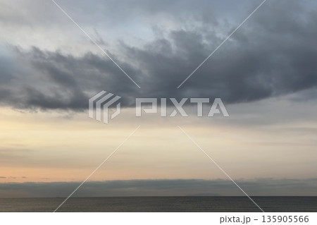 やわらかな朝の光と雲の帯が広がる穏やかな海の景色 やわらかな朝の光と雲の帯が広がる穏やかな海の景色 135905566