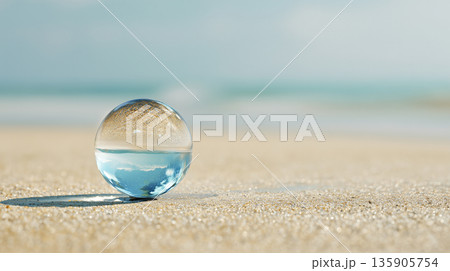 砂浜に置かれたガラス玉に海が映り込む静かな癒しの写真素材、背景 135905754