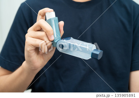 Asthma and chronic obstructive pulmonary disease COPD, Asian young man using metered dose inhaler MDI. Asthma and chronic obstructive pulmonary disease COPD, Asian young man using metered dose inhaler MDI. 135905891