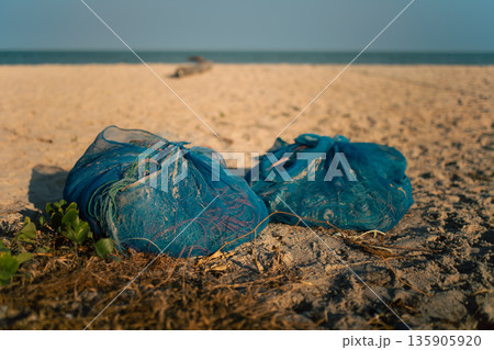Blue Fishing Nets Prepared on Sandy Beach for Daily Harvest 135905920