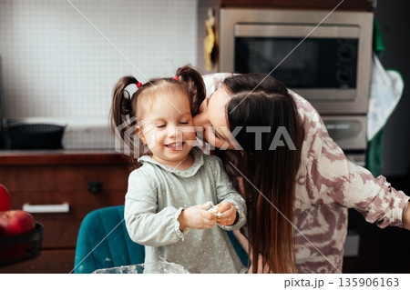 Mother and daughter share a moment in the kitchen while making dough together during a fun and creative activity in the afternoon 135906163