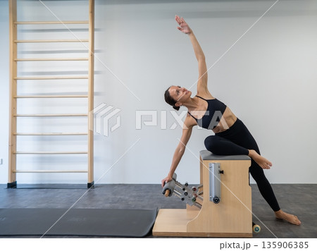 Caucasian woman doing Pilates on classic chair. 135906385