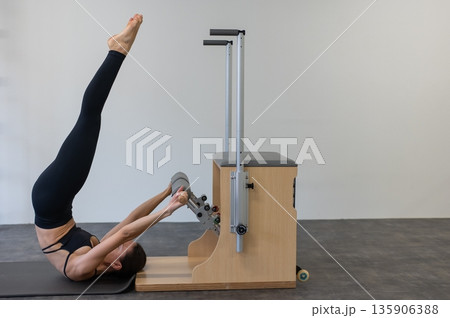 Caucasian woman doing Pilates on classic chair. Caucasian woman doing Pilates on classic chair. 135906388