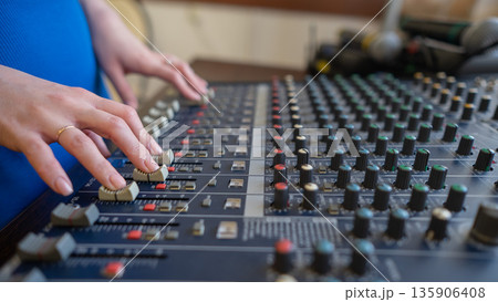 Hands Adjusting Sound Levels on Mixing Console.  135906408