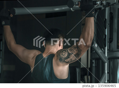The back of bodybuilders exercise with lifting weights on an exercising machine in gym or fitness club. 135906465