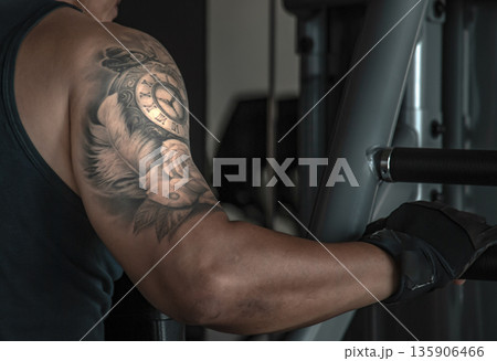 Closeup of bodybuilders exercise with lifting weights on an exercising machine in gym or fitness club. Closeup of bodybuilders exercise with lifting weights on an exercising machine in gym or fitness club. 135906466