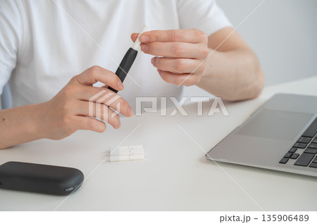 A woman inserts a cigarette stick into a tobacco heating system. Electronic cigarette. 135906489