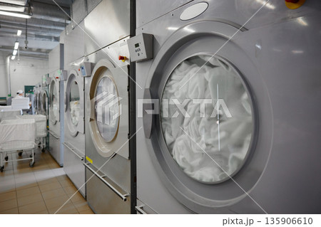 A row of washing machines is perfectly lined up in a laundromat 135906610