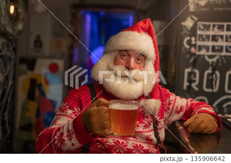 Santa Claus drinking beer at a bar.  135906642