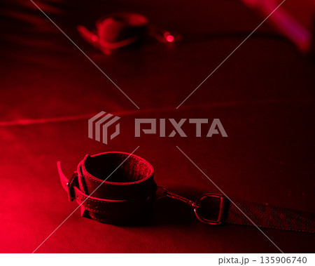 Close-up of leather handcuffs for BDSM games under red light. Close-up of leather handcuffs for BDSM games under red light. 135906740