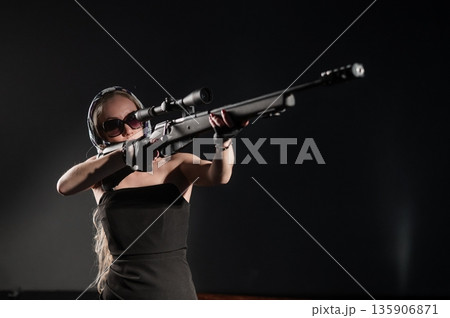 A Caucasian woman practicing shooting with a rifle and scope.  135906871