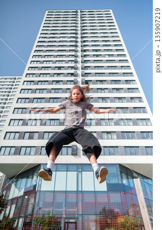 A girl jumps on an outdoor trampoline. 135907219