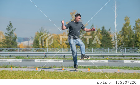 A Caucasian man rollerblades around the slalom course. A Caucasian man rollerblades around the slalom course. 135907220
