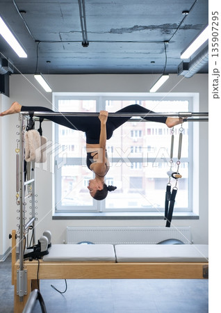 Caucasian woman doing pilates on reformer. Caucasian woman doing pilates on reformer. 135907295