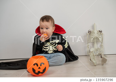 Cute caucasian boy in dracula halloween costume holding candy basket on white background. Cute caucasian boy in dracula halloween costume holding candy basket on white background. 135907296